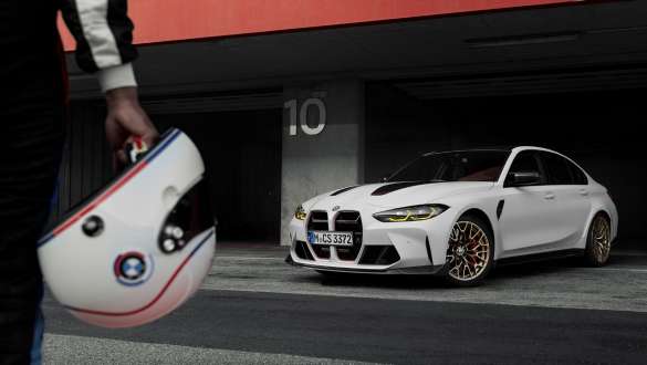 Pacchetto della dinamica di guida specifico per del versioni CS della BMW M3 CS G80 Pacchetto della dinamica di guida specifico per del versioni CS della BMW M3 CS G80 CS - Persona con casco in mano e BMW M3 CS sullo sfondo