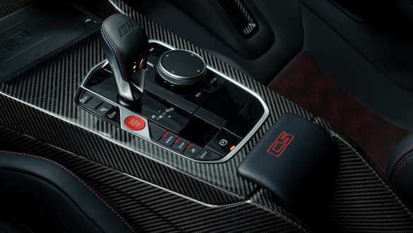Consolle centrale di carbonio con logo CS rosso della BMW M3 CS G80 Primo piano della plancia strumenti con consolle centrale in carbonio con logo CS rosso della BMW M3 CS G80