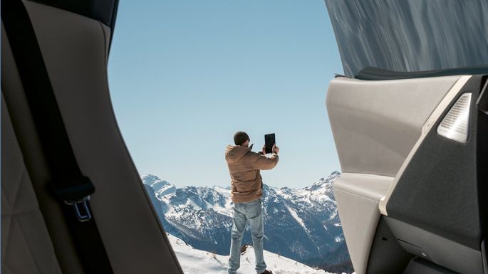 portiera aperta su una persona davanti al panorama montano in inverno Controllo vacanze BMW Vista dalla BMW con portiera aperta su una persona davanti al panorama di montagna in inverno