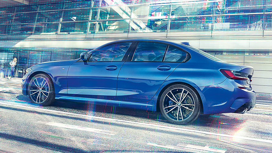 BMW Serie 3 Berlina (G20) di giorno davanti a un edificio con facciate in vetro Ripresa laterale da ferma della BMW Serie 3 Berlina Portimao Blue (G20) di giorno davanti a un edificio con facciate in vetro