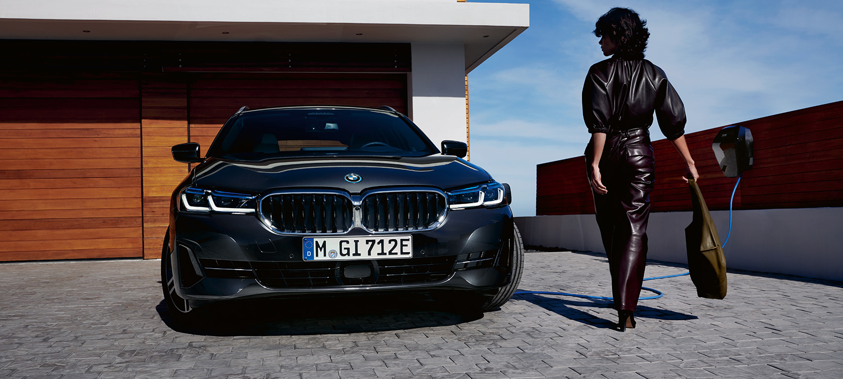BMW Serie 5 Touring ibrida Plug-in 2021 G31 Vista anteriore in ricarica BMW Serie 5 Touring ibrida Plug-in 2021 G31 LCI Vista anteriore in ricarica con fotomodella