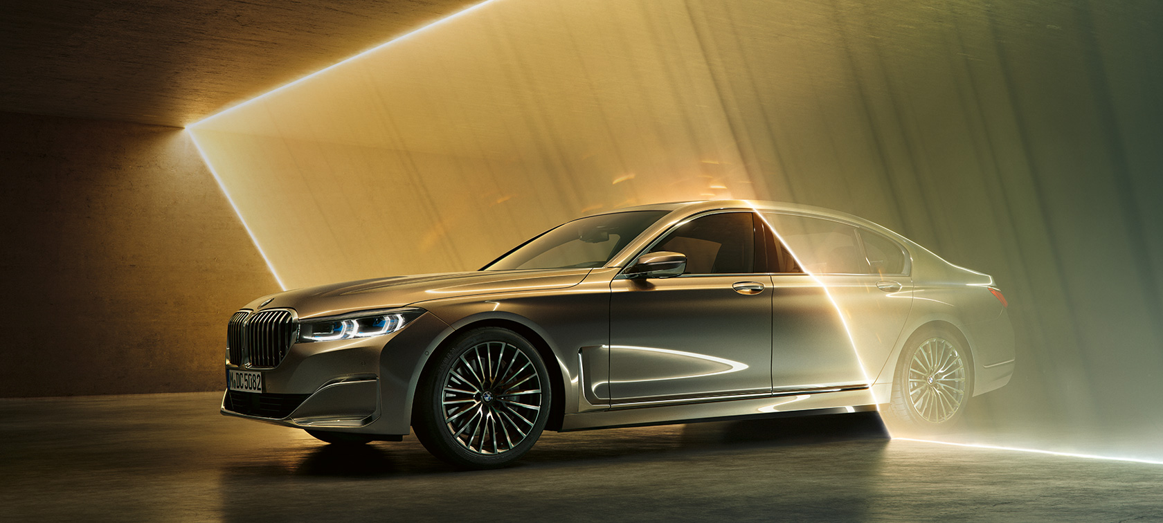 BMW Serie 7 Berlina, berlina di lusso, vista anteriore a tre quarti BMW Serie 7 Berlina, berlina di lusso: BMW grigia, vista anteriore a tre quarti, circondata da fasci di luce