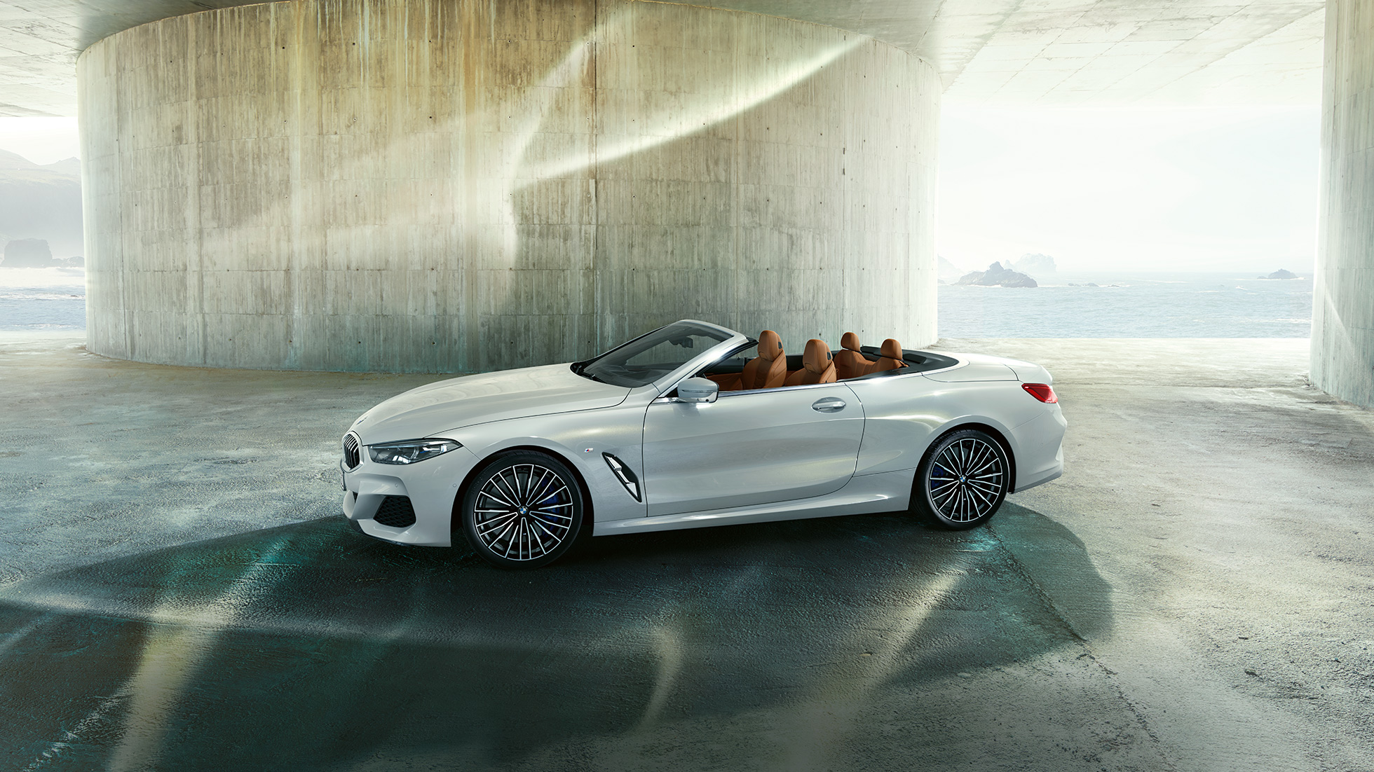 BMW M850i xDrive in Mineral White metallic, vista laterale con capote in tessuto aperta. BMW M850i xDrive in Mineral White metallic, vista laterale con capote in tessuto aperta.