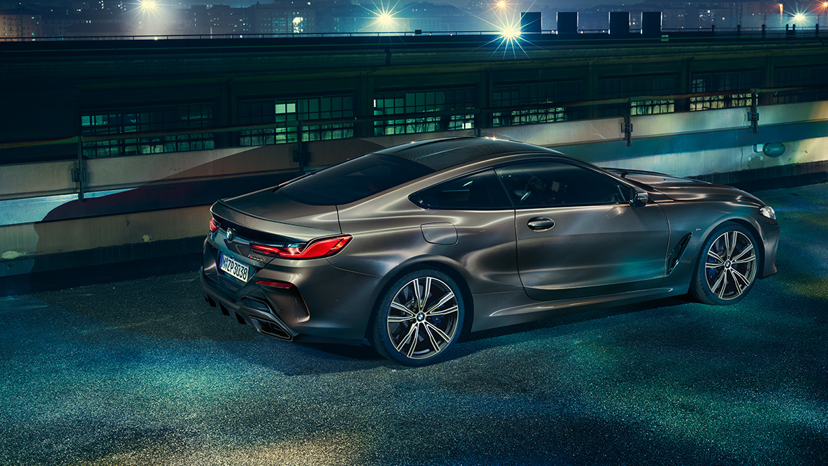 Vue latérale de la BMW Série 8 Coupé à l’arrêt. G15 La BMW Série 8 Coupé avec équipement BMW Individual, photographiée de profil à l'arrêt dans un décor urbain de nuit. G15