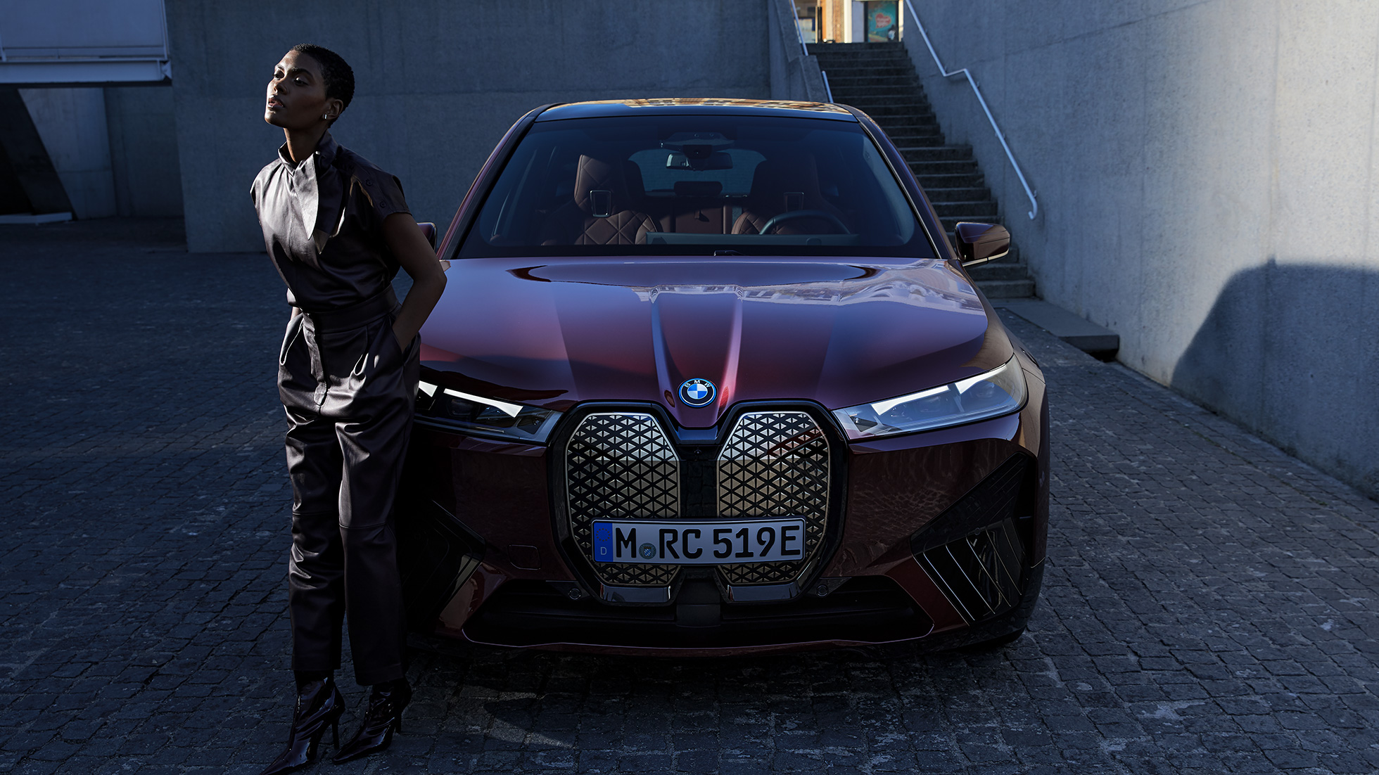 BMW iX Frontansicht mit Model BMW iX Aventurinrot i20 Frontansicht mit Model
