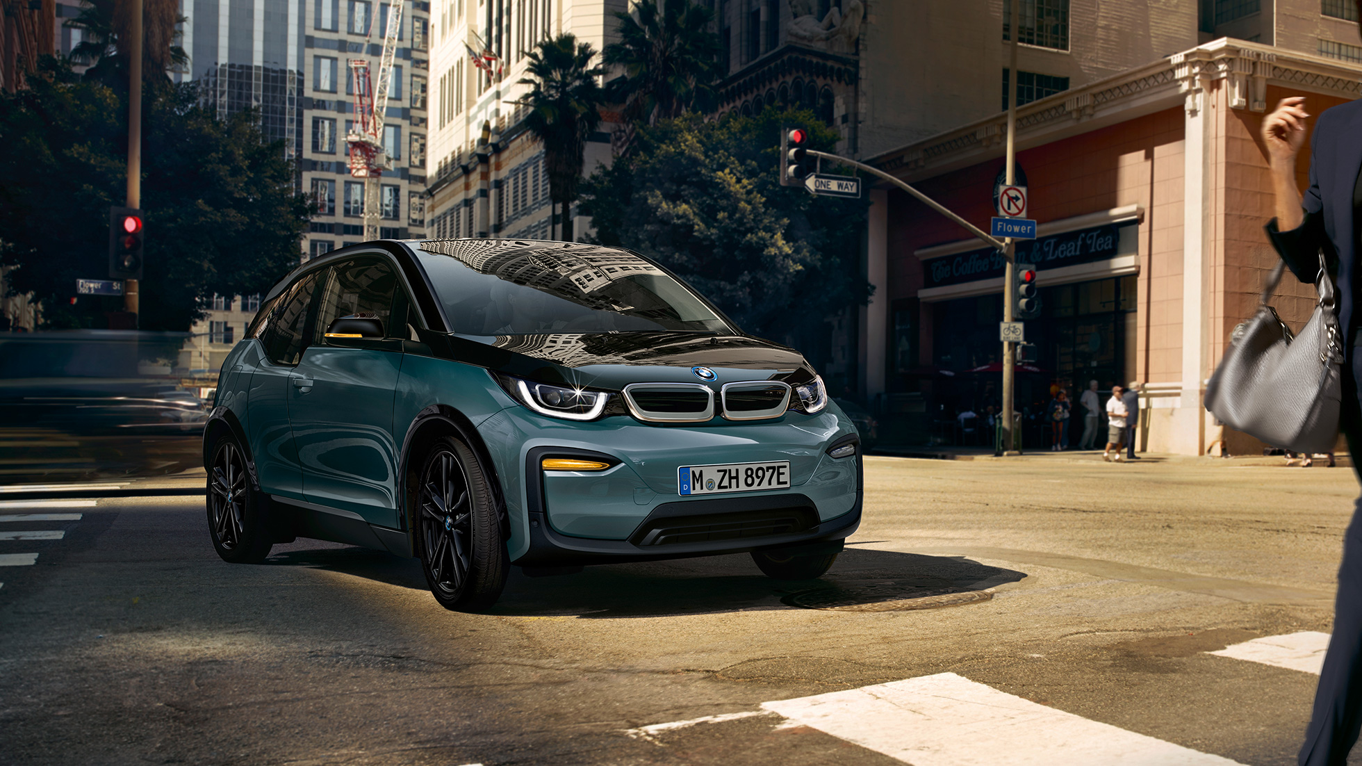 BMW i3 2018 vista anteriore a tre quarti in viaggio I01 BMW i3 I01 2018 Jucaro Beige con profilo in Frozen Grey metallizzato vista anteriore a tre quarti in viaggio su sfondo urbano I01