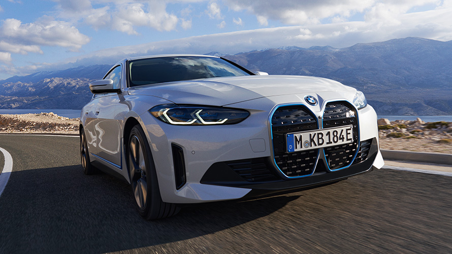 Vista anteriore a tre quarti della BMW i4 eDrive40 G26 2021 in movimento BMW i4 eDrive40 G26 2021 Mineral White vista anteriore a tre quarti in movimento