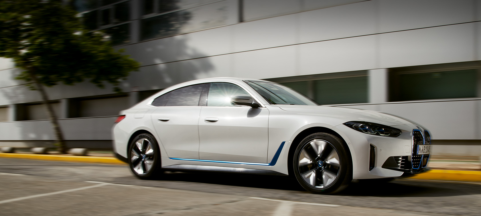 BMW i4 eDrive40 G26 2021 Dreiviertel-Seitenansicht fahrend vor Gebäude BMW i4 eDrive40 G26 2021 Dreiviertel-Seitenansicht fahrend vor Gebäude