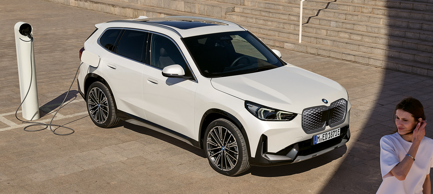 BMW iX1 U11 BEV Seitenansicht ladend BMW iX1 U11 BEV 2022 Mineralweiss metallic Zwei drittel Seitenansicht ladend Treppen