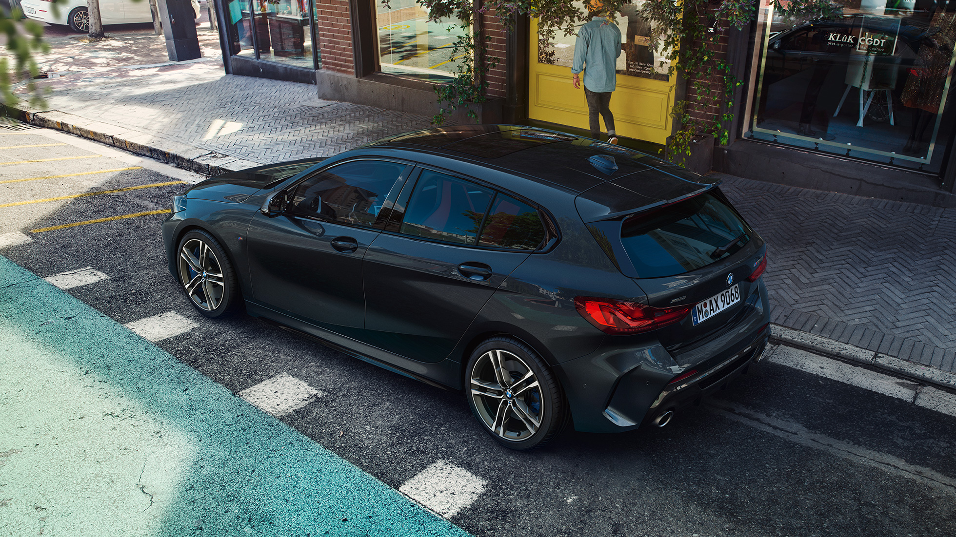 BMW M135i xDrive, mentre sta parcheggiando. F40 BMW M135i xDrive in Sapphire Black metallizzato, vista laterale con prospettiva a volo di uccello, mentre sta parcheggiando. F40