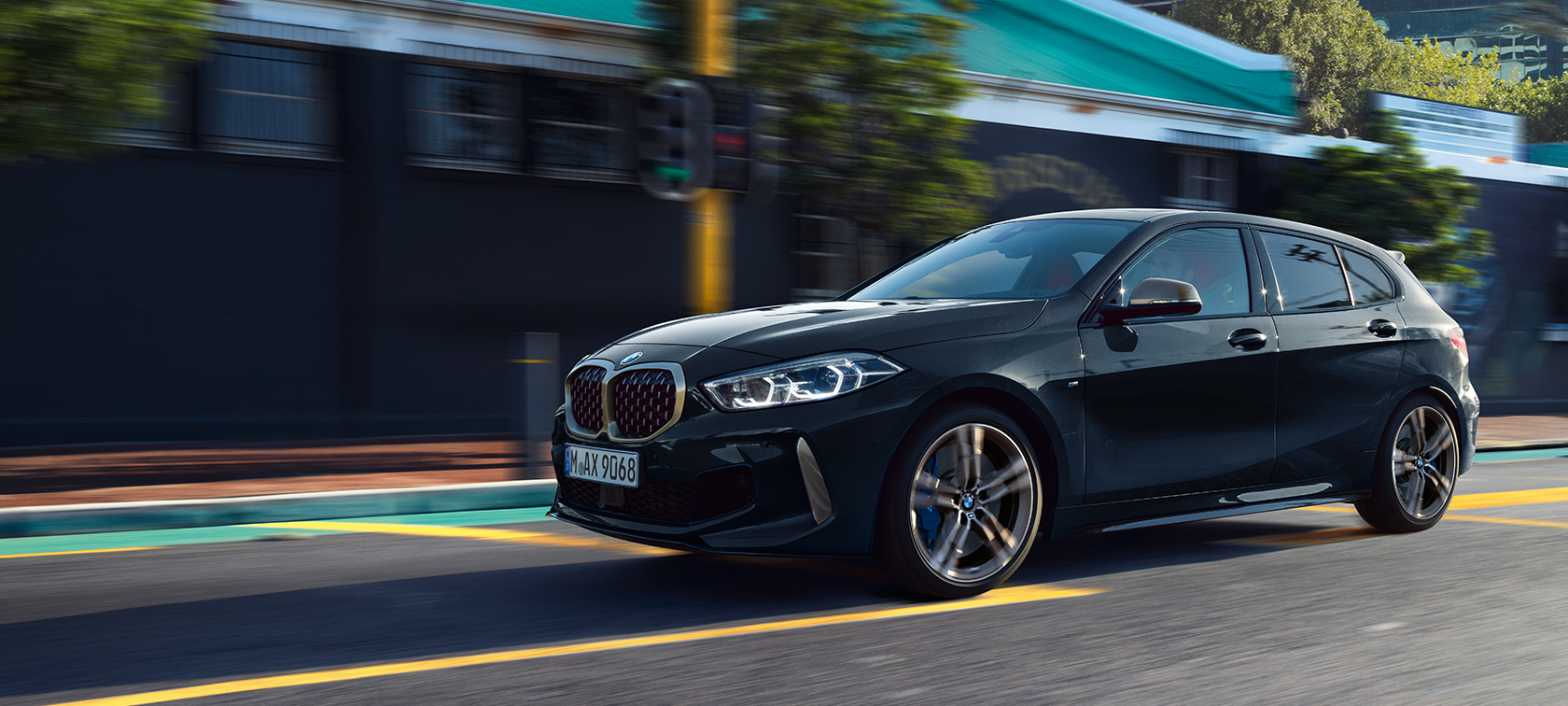 Nuova BMW M135i xDrive. Nuova BMW M135i xDrive in Sapphire Black metallizzato, vista laterale a tre quarti, in movimento.