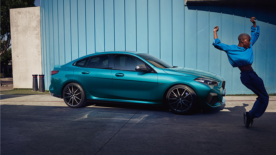BMW M235i xDrive Gran Coupé F44 Vue de profil avec femme à l'avant-plan BMW M235i xDrive Gran Coupé F44 Snapper Rocks Blau metallic Vue de profil avec femme à l'avant-plan