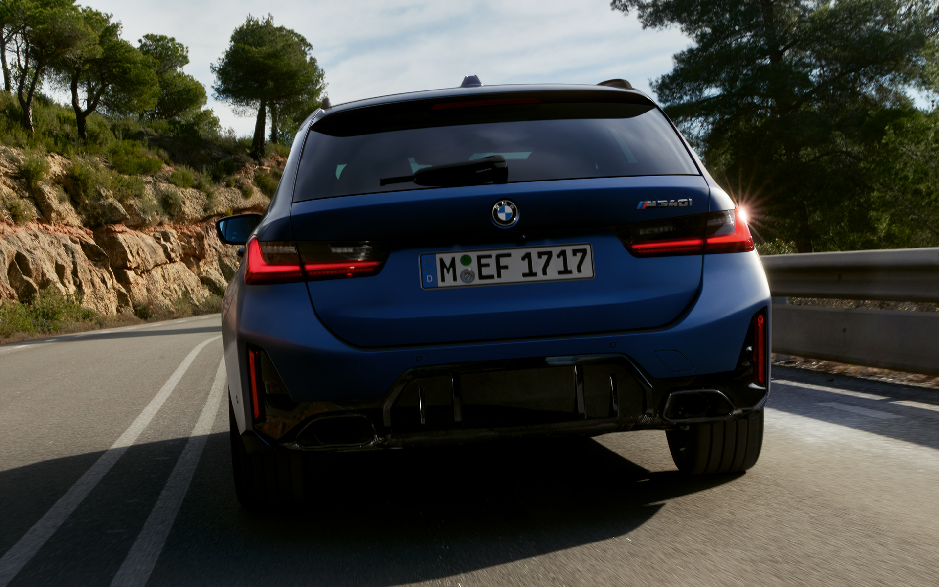 Vista posteriore in movimento su strada della BMW M340i xDrive Touring G21 Vista posteriore in movimento su strada della BMW M340i xDrive Touring G21 Frozen Tanzanite Blue
