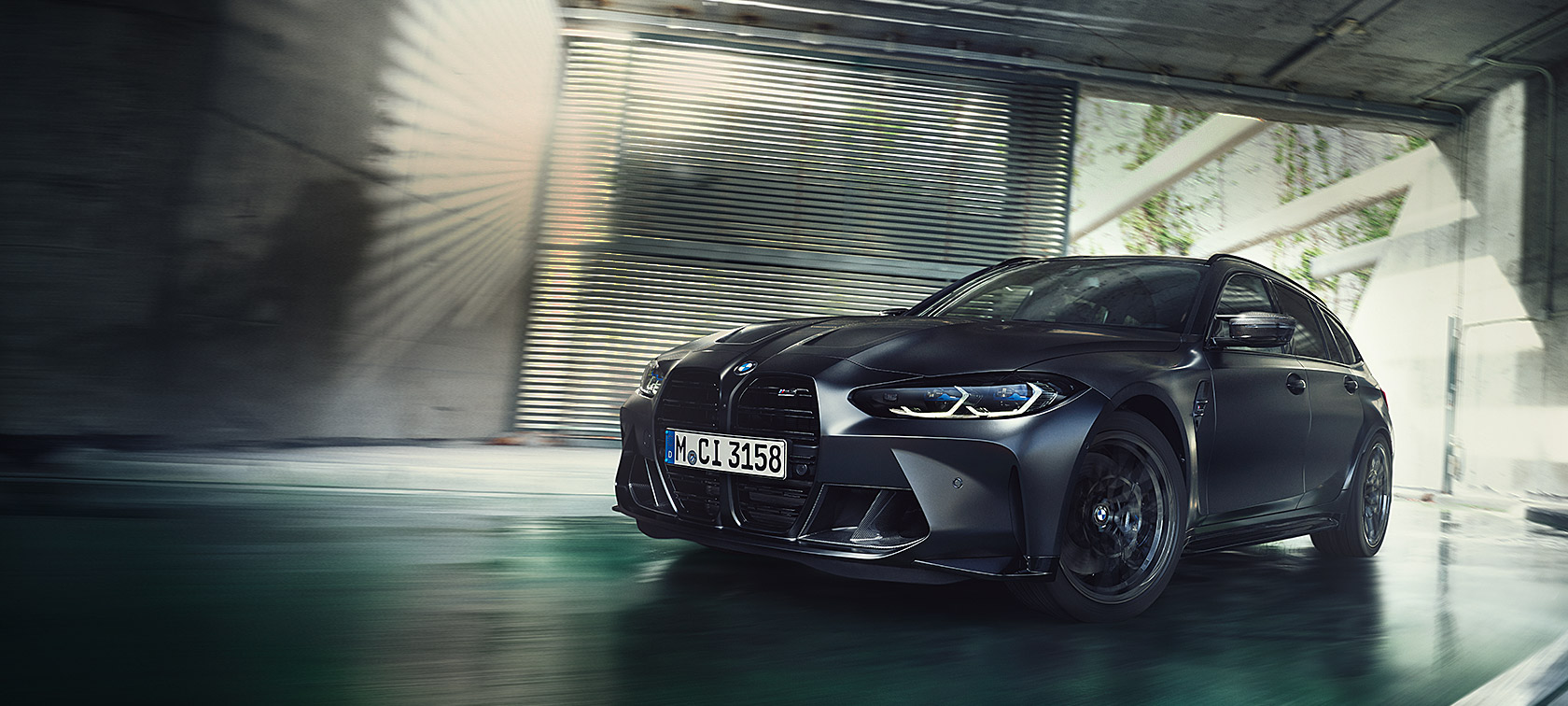 Vista frontale a tre quarti in movimento della BMW M3 Competition Touring G81 BMW Individual Frozen Black metallizzato