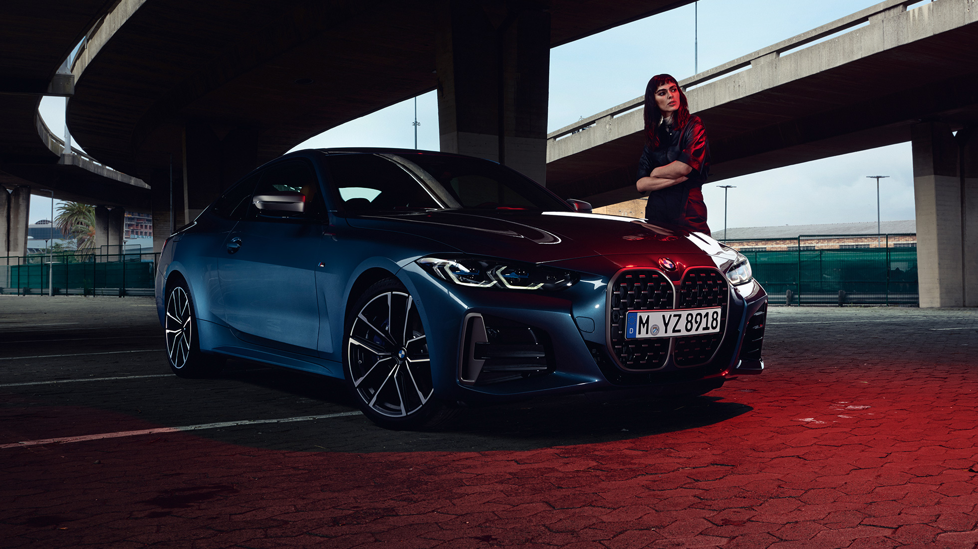 Model steht neben BMW M440i xDrive Coupé G22 2020 Dreiviertel-Seitenansicht BMW M440i xDrive Coupé Arctic Race Blue metallic G22 2020 Dreiviertel-Seitenansicht mit Model