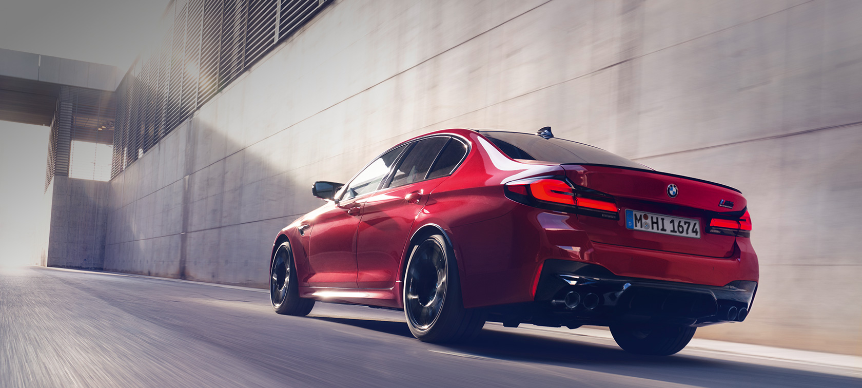 BMW M5 Competition F90 LCI Facelift 2020 vista posteriore a tre quarti in movimento F90 BMW M5 Competition F90 LCI Facelift 2020 BMW Individual Imola Red vista posteriore a tre quarti in movimento F90