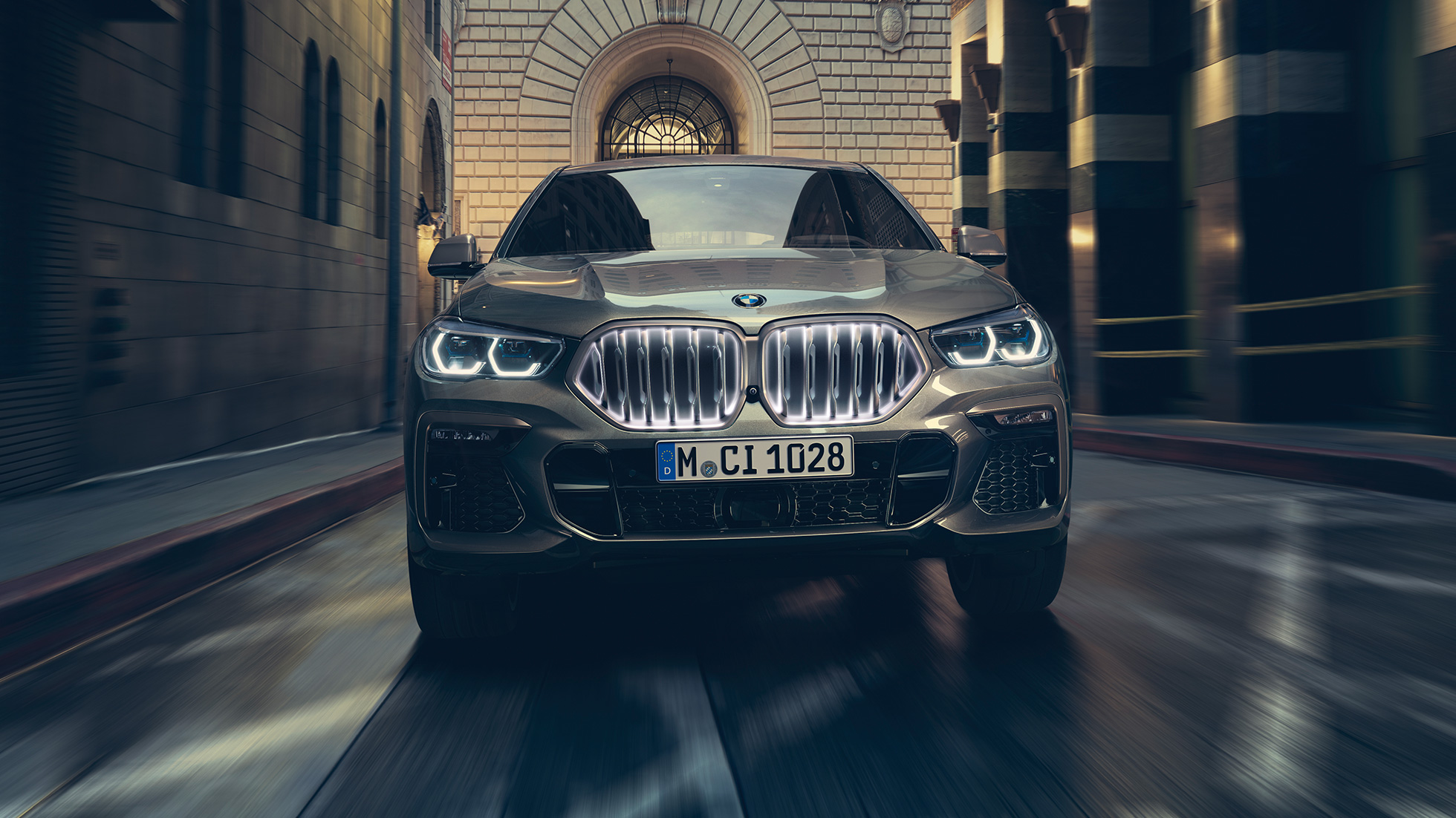 BMW X6 M50i mit BMW ‚Iconic Glow‘ Niere. BMW X6 M50i in Front-Perspektive vor urbaner Kulisse.