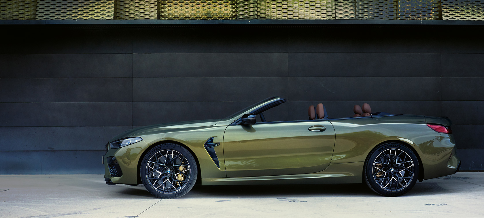 BMW M8 M Competition Cabrio F91 LCI restylage 2022 vue de profil en stationnement BMW M8 M Competition Cabrio F91 LCI restylage 2022 BMW Individual Brass metallic Vue de profil en stationnement avec portière ouverte et mannequin femme