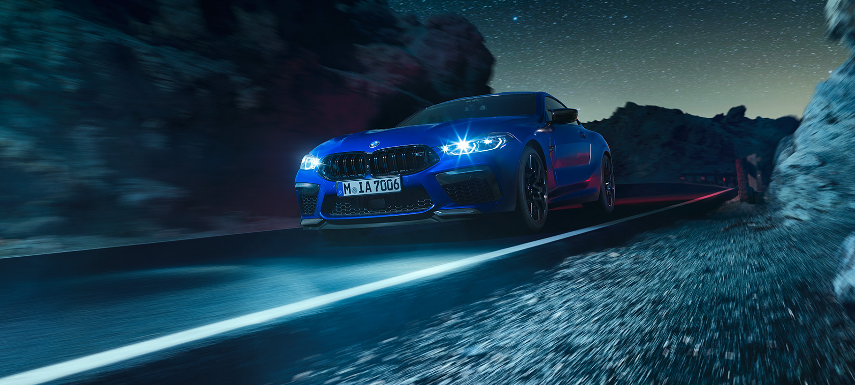BMW M8 Competition Coupé, vue de trois quarts avant. F92 La première BMW M8 Competition Coupé en Marina Bay Blau metallic, vue de trois quarts avant, en marche, de nuit. F92