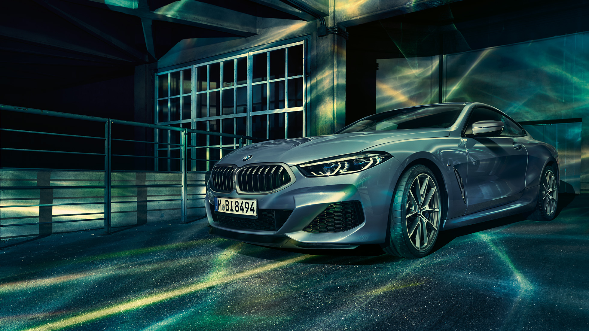 BMW M850i xDrive Coupé, vista frontale di tre quarti. G15 BMW M850i xDrive Coupé in Barcelona Blue metallizzato, vista frontale di tre quarti in sosta davanti a un edificio. G15