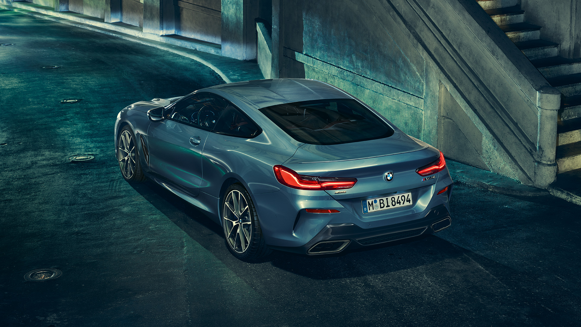 BMW M850i xDrive Coupé, vista posteriore di tre quarti da sinistra. G15 BMW M850i xDrive Coupé in Barcelona Blue metallizzato, vista posteriore di tre quarti da sinistra, in sosta di notte. G15