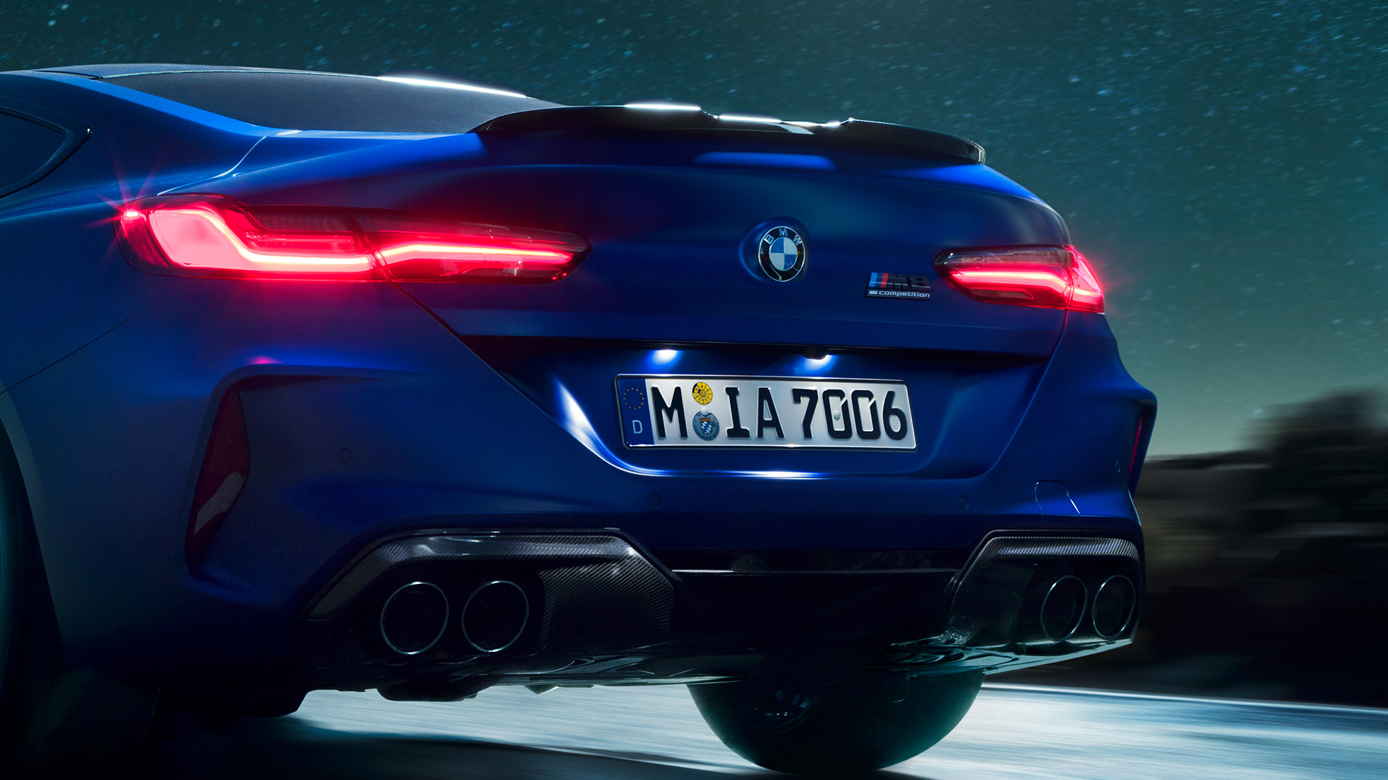 Diffusore M in carbonio nero. F92 BMW M8 Competition Coupé in Marina Bay Blue metallizzato, primo piano del posteriore di notte con diffusore M in carbonio nero. F92