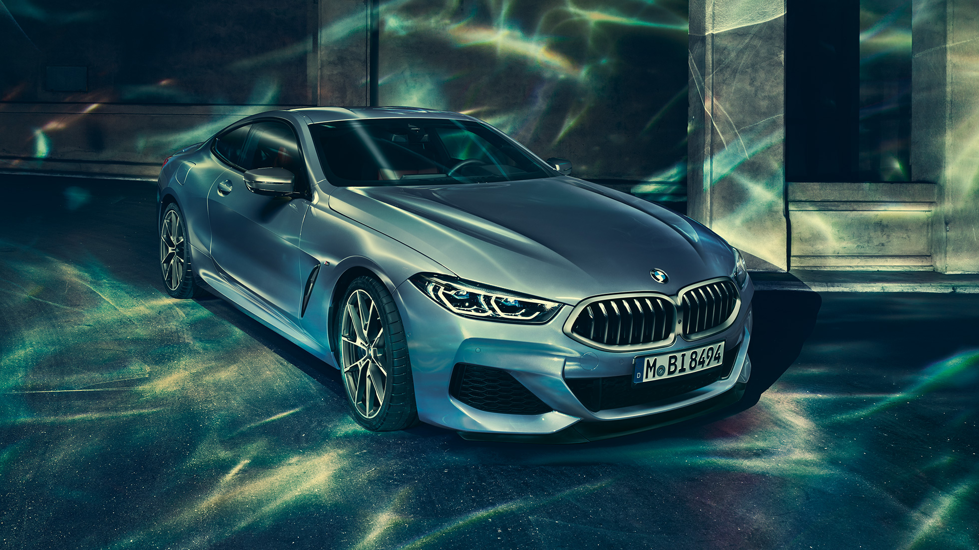 BMW M850i xDrive Coupé, vista frontale di tre quarti da sinistra. G15 BMW M850i xDrive Coupé in Barcelona Blue metallizzato, vista frontale di tre quarti da sinistra, in sosta davanti a un edificio. G15
