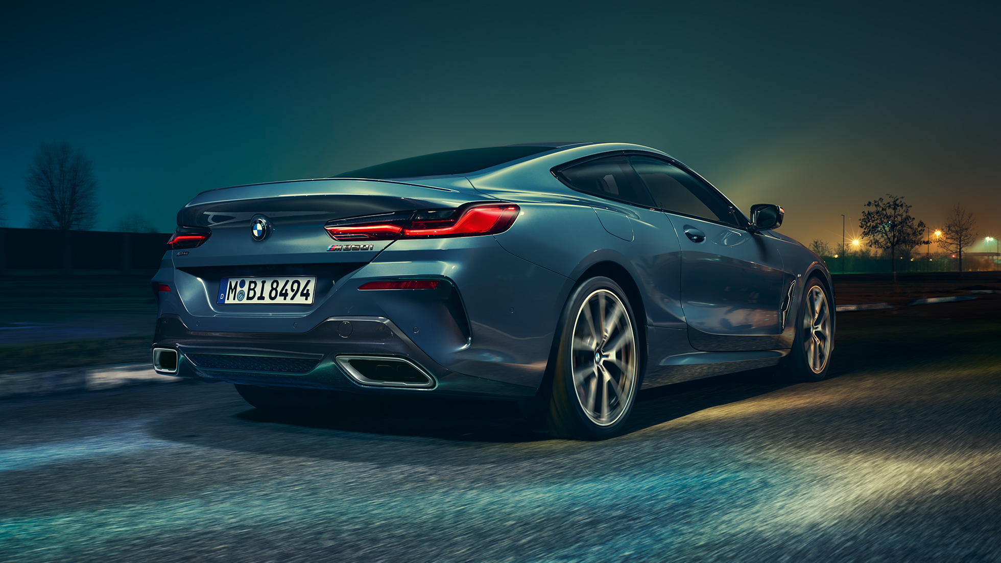 BMW M850i xDrive Coupé, vista posteriore. G15 BMW M850i xDrive Coupé in Barcelona Blue metallizzato, vista posteriore, in marcia di notte. G15