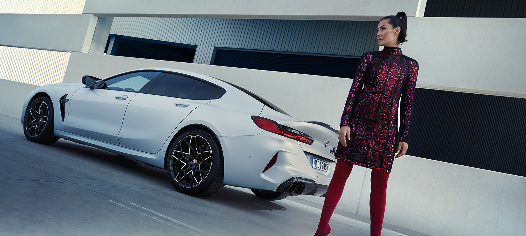 Dreiviertel-Heckansicht BMW M8 Competition Gran Coupé F93 LCI 2022 BMW M8 Competition Gran Coupé F93 LCI Facelift 2022 BMW Individual Frozen Brilliant White metallic Dreiviertel-Heckansicht mit weiblichem Model neben Fahrzeug
