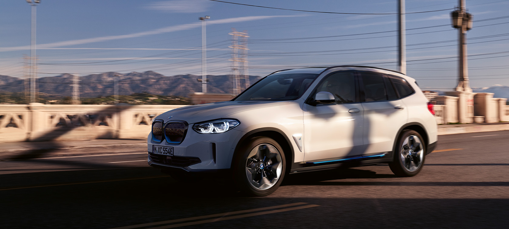 BMW iX3 G08 Dreiviertel-Frontansicht fahrend auf der Strasse BMW iX3 G08 2020 Mineralweiss metallic Dreiviertel-Frontansicht fahrend auf der Strasse