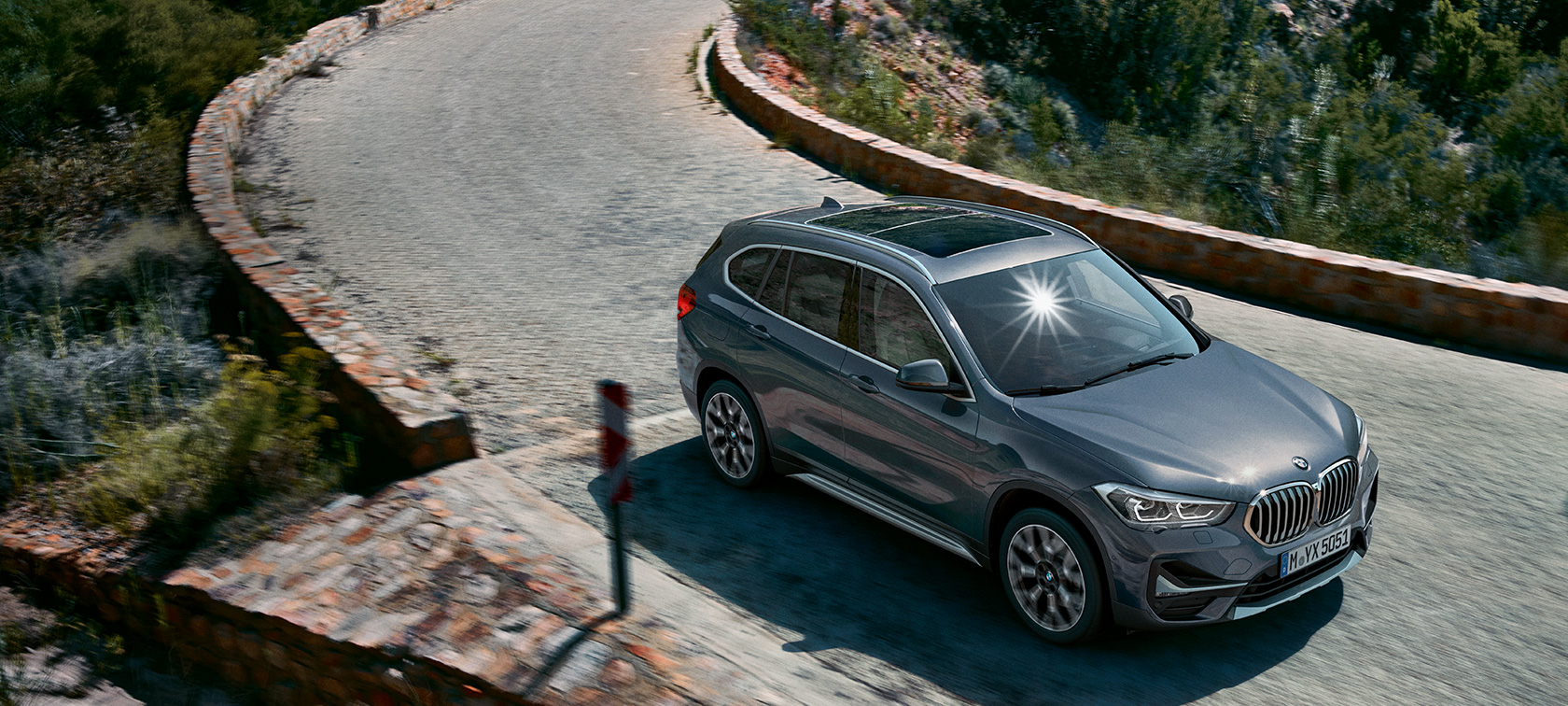 BMW X1, vista anteriore a tre quarti. F48 BMW X1, vista anteriore a tre quarti in movimento in un paesaggio montano. F48