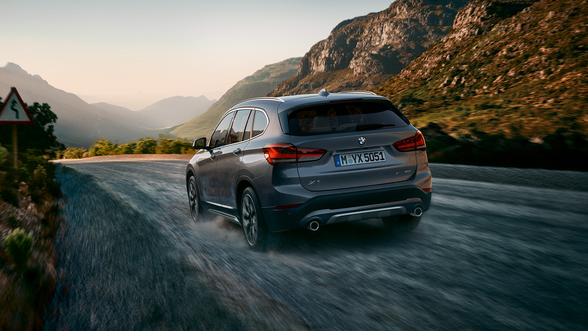 BMW X1, Dreiviertel-Heckansicht F48. BMW X1, Dreiviertel-Heckansicht fahrend vor Gebirgskulisse F48.