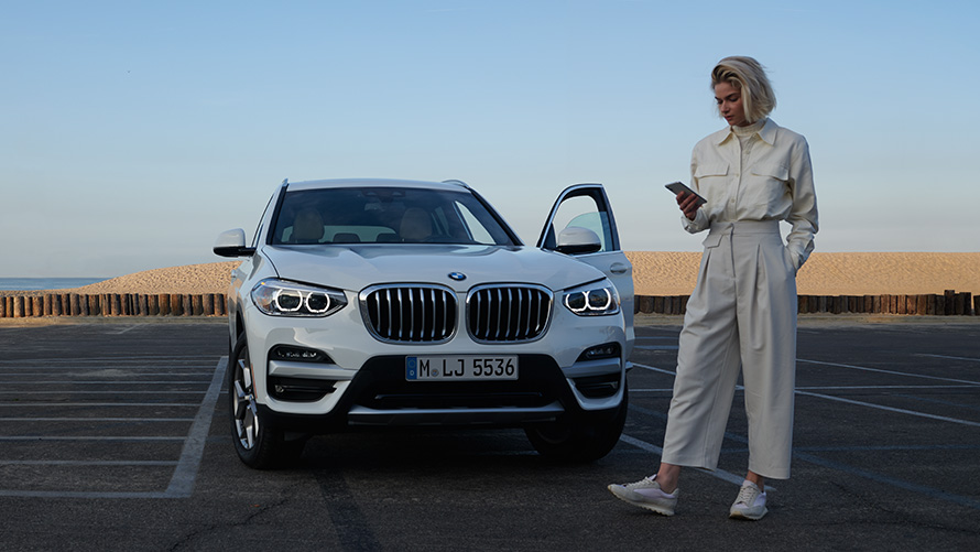 BMW X3 G01 App Brochures femme à côté d'une BMW 2021 BMW X3 G01 App Brochures 2021
