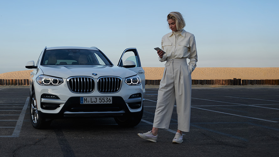 BMW X4 G02 App Brochures 2021 BMW X4 G02 App Brochures femme à côté d'une BMW 2021