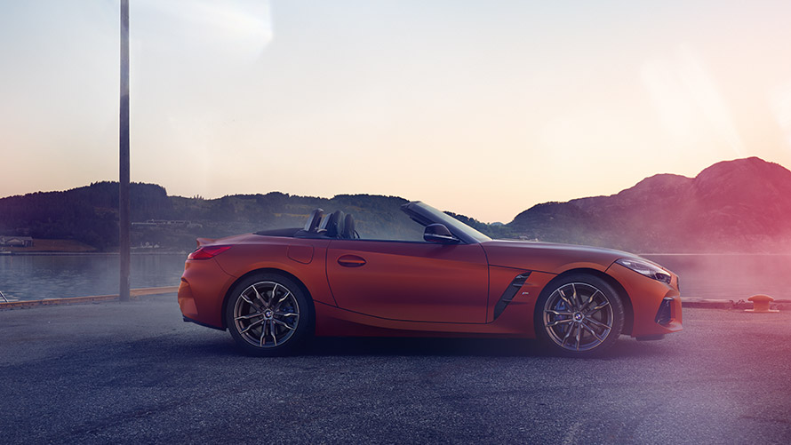 Orange BMW Z4 First Edition à l'arrêt dans un virage BMW Z4 First Edition orange à l'arrêt dans un virage, paysage de montagnes
