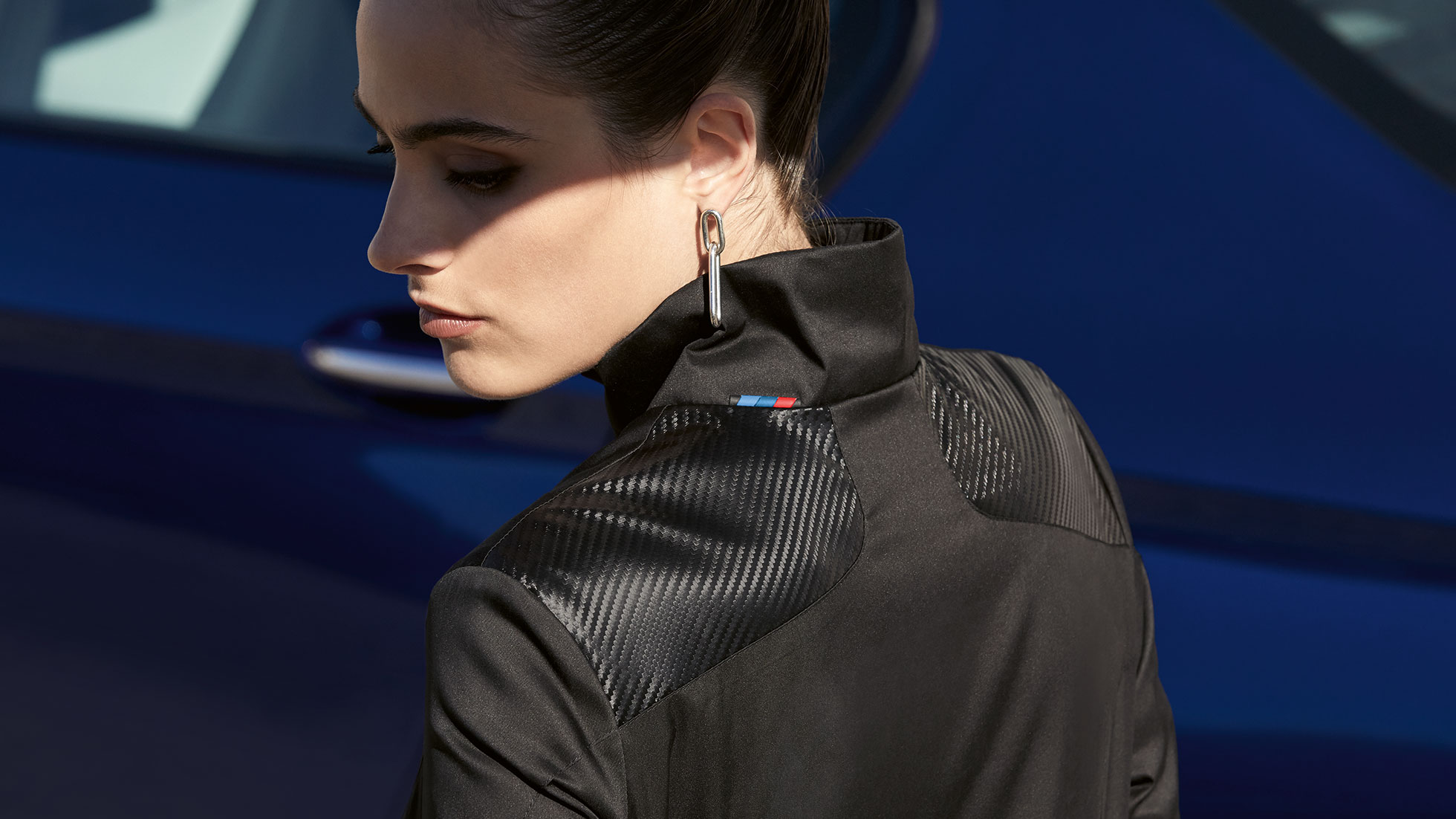 BMW M Jacke Damen. Frau trägt BMW M Jacke Damen aus der BMW M Collection. Detail Materialmix.