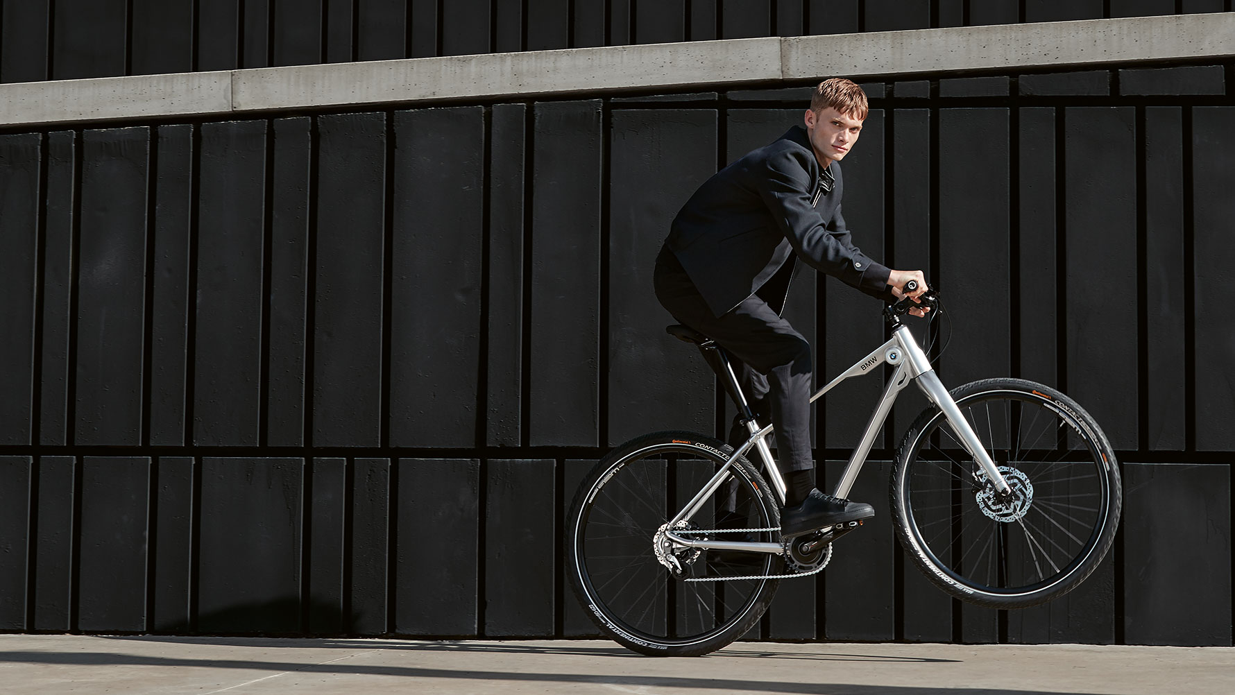 Zu sehen ist ein junger Mann, der auf einem BMW Cruise Bike einen dynamischen Wheelie macht. Zu sehen ist ein junger Mann, der auf einem BMW Cruise Bike einen dynamischen Wheelie macht.