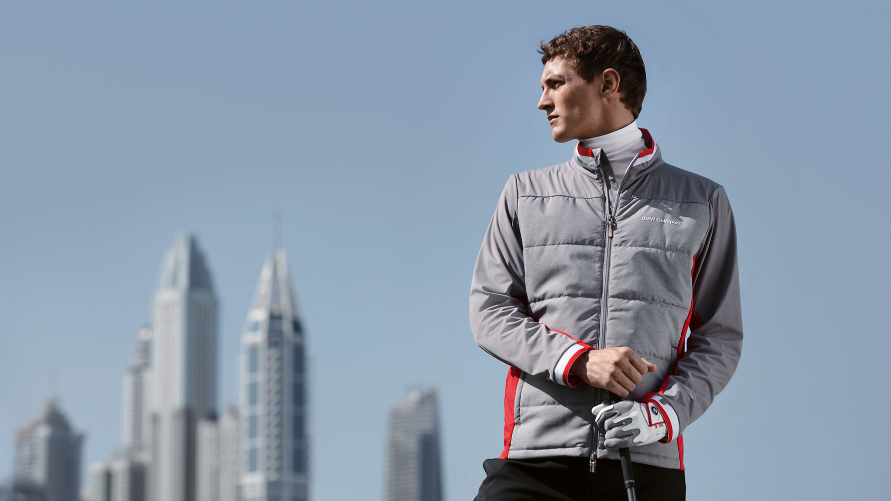 Auf dem Bild präsentiert ein Mann vor der Skyline einer Grossstadt Teile der BMW Golfsport Collection. Auf dem Bild präsentiert ein Mann vor der Skyline einer Grossstadt Teile der BMW Golfsport Collection.