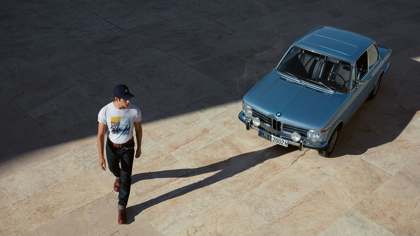 Mann trägt BMW Classic T-Shirt Herren aus der BMW Classic Collection und bewundert einen BMW Oldtimer. Mann trägt BMW Classic T-Shirt Herren aus der BMW Classic Collection und bewundert einen BMW Oldtimer.