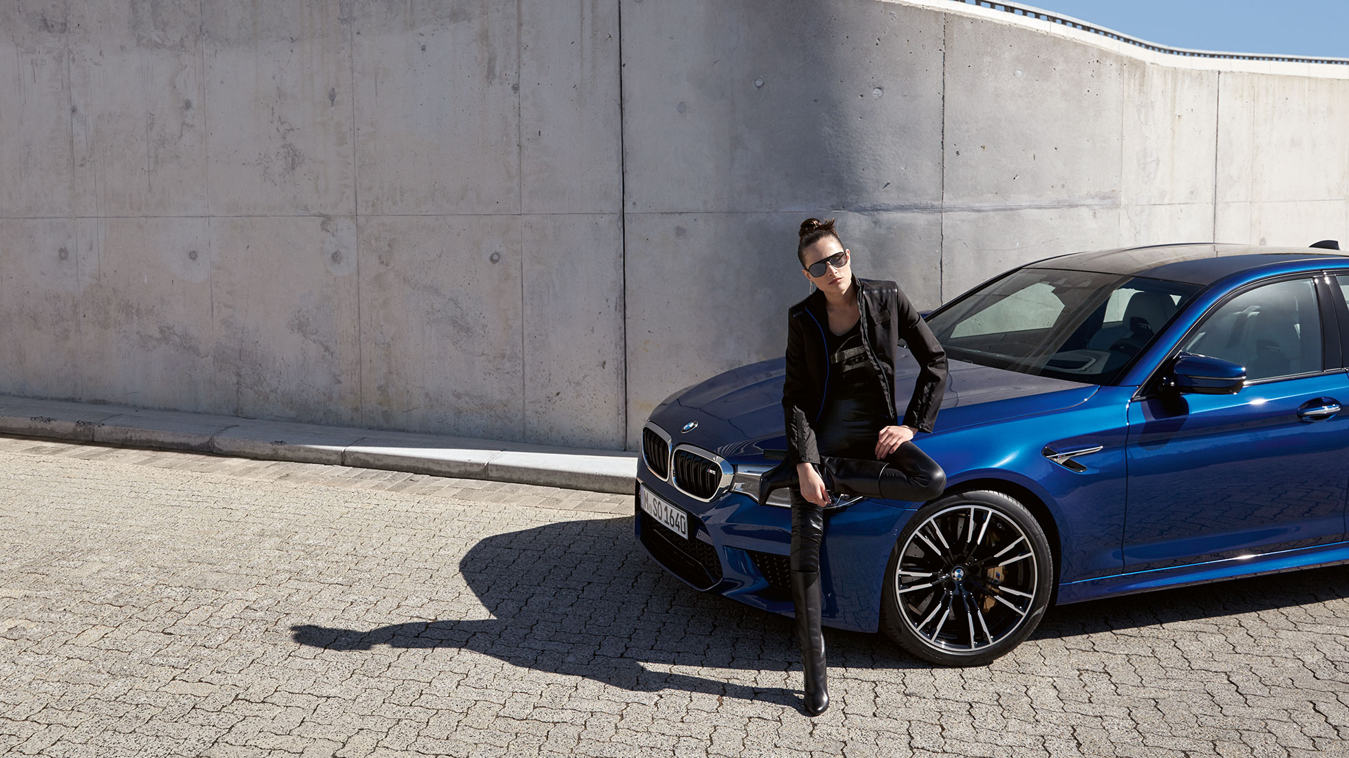 BMW M Collection. Eine junge Frau zeigt die BMW M Jacke für Damen.