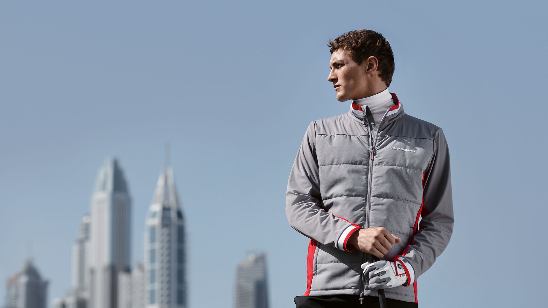 Un uomo presenta i prodotti della BMW Golfsport Collection davanti allo skyline di una grande città. Un uomo presenta i prodotti della BMW Golfsport Collection davanti allo skyline di una grande città.