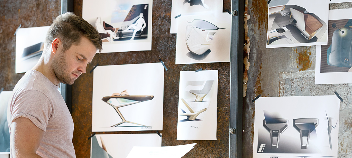 Schizzi di BMW Vision iNEXT Uomo davanti al muro con gli schizzi di BMW Vision iNEXT