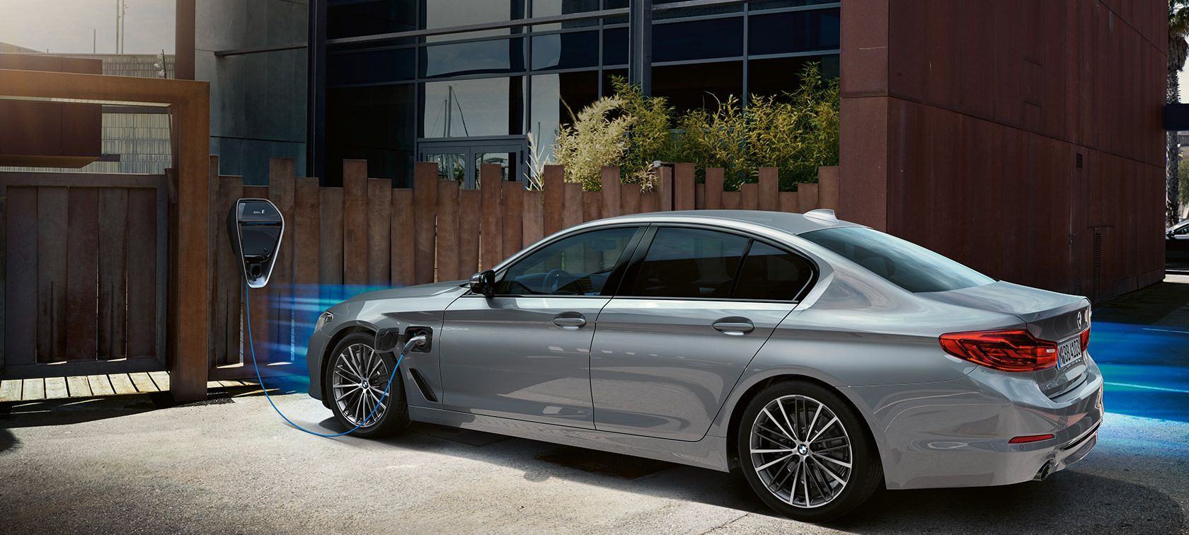BMW 530e vor Ladestation. BMW 530e in Dreiviertel-Heck an der Ladestation.