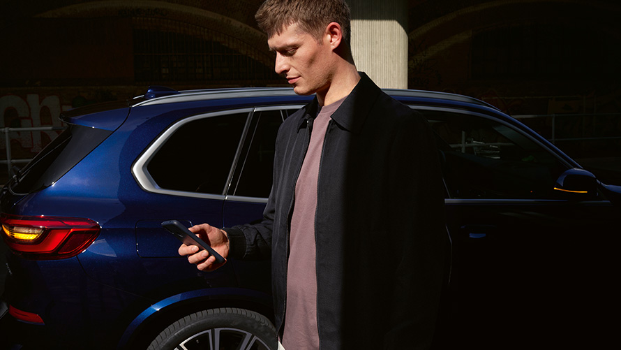BMW Digital Key – bis zu fünf Nutzer einrichten BMW Digital Key bis zu fünf Nutzer einrichten Mann mit Smartphone vor BMW X5