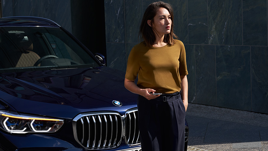 Service & soccorso stradale Una donna è seduta davanti alla propria BMW rossa e utilizza Service & soccorso stradale