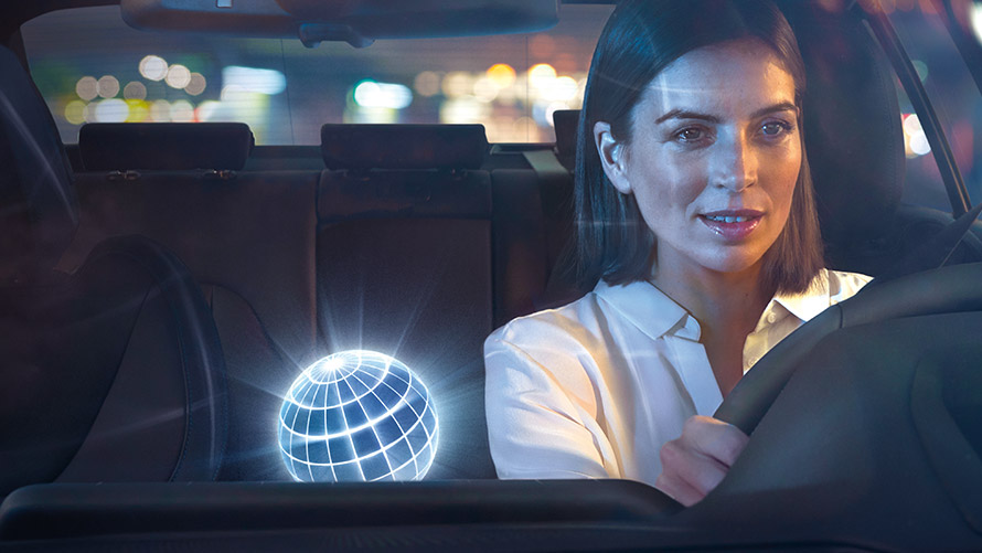 BMW Intelligent Personal Assistant, Natural Interaction Frau fährt in BMW bei nächtlicher Kulisse.