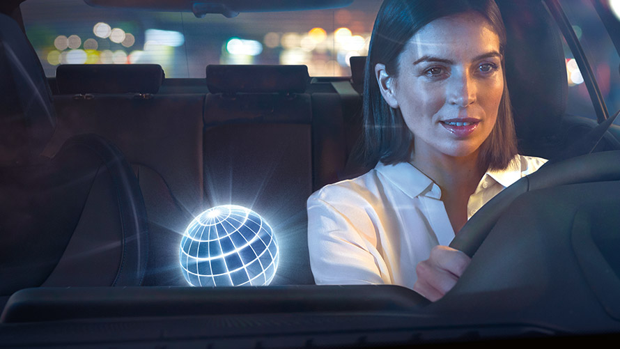 BMW Intelligent Personal Assistant Frau fährt in BMW bei nächtlicher Kulisse.