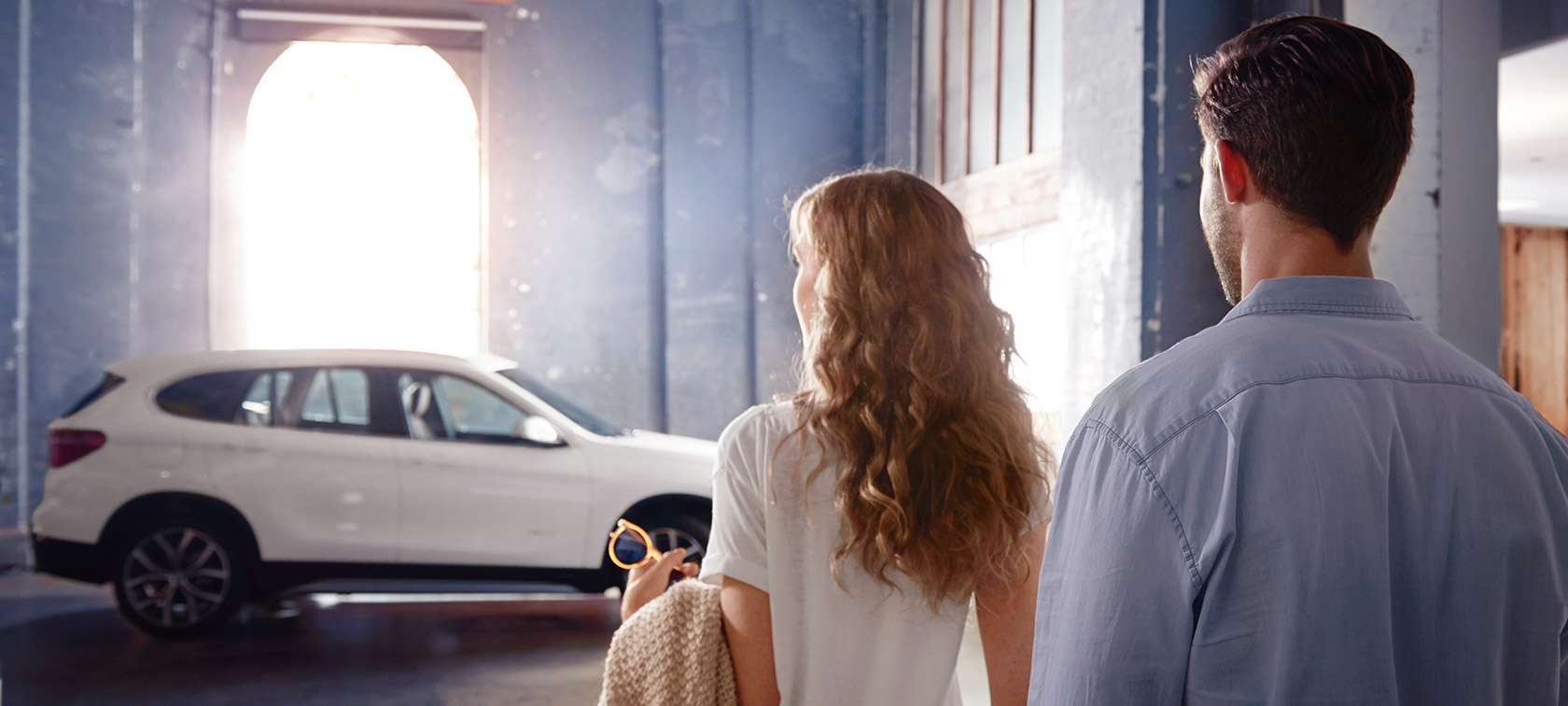 Un couple devant une BMW dans un bâtiment BMW Financial Services Un couple devant une BMW dans un bâtiment