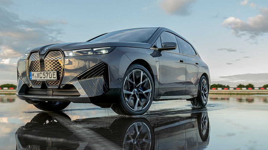 Cerchio BMW, vista anteriore a tre quarti della BMW iX (i20) su strada bagnata Cerchio BMW, vista anteriore a tre quarti della BMW iX (i20) su strada bagnata