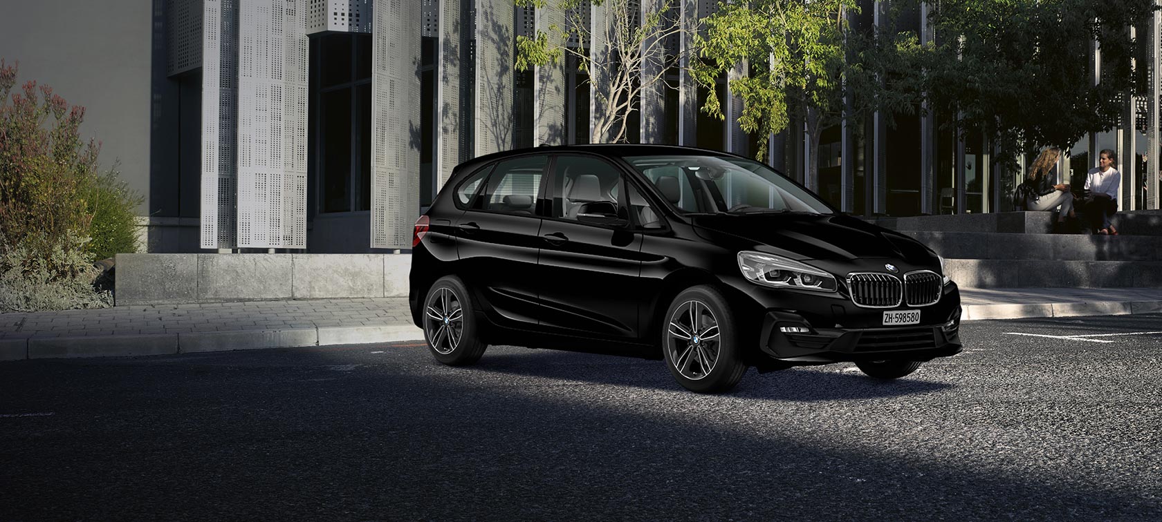 Donne su una scala di pietra BMW Serie 2 Active Tourer Swiss Advantage Sport+ Donne su una scala di pietra BMW Serie 2 Active Tourer Swiss Advantage Sport+ nera vista laterale edificio moderno parcheggio